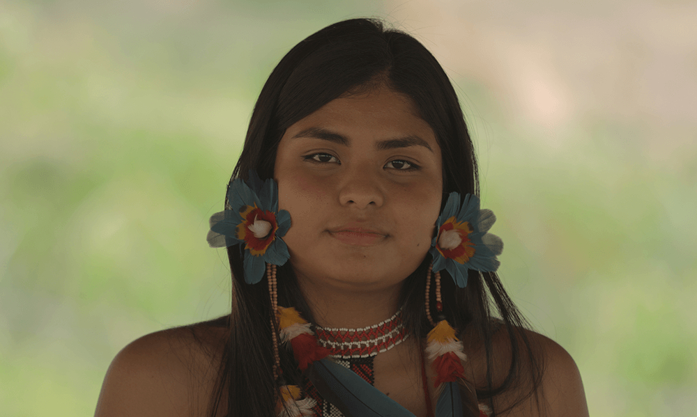 Uma jovem mulher indígena olhando seriamente para quem bateu a foto