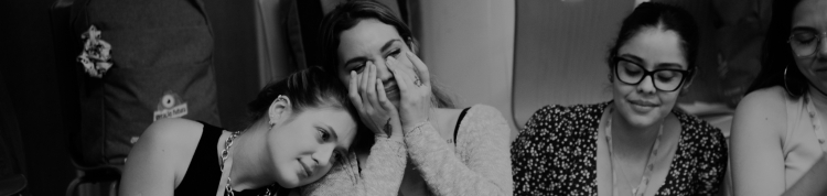 Fotos dos bastidores, três meninas sentadas no chão. 