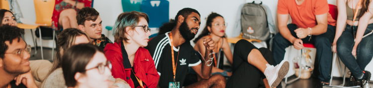 Fotos dos bastidores com um grande grupo de jovens sentados no chão