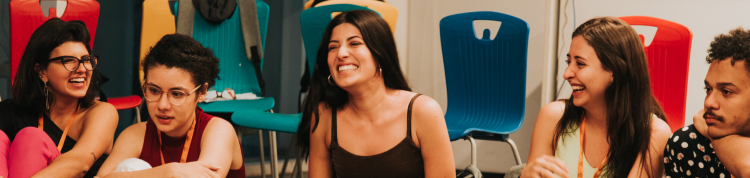 Fotos dos bastidores com um grande grupo de jovens sentados no chão